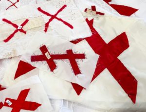 a pile of quilt blocks, pairs of red x's sewn to a white base