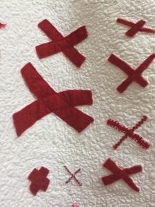 closeup photo of a quilt - white background covered with pairs of red X's