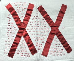 white quilt covered with pairs of red X's