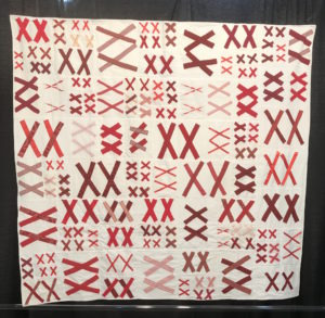 white quilt embellished with pairs of red X's