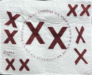 white quilt decorated with pairs of red X's