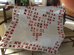 white quilt base with pairs of red X's forming a heart in the center and pairs of red X's forming a frame around the outer edges