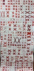 white quilt with pairs of red X's