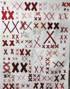 a white quilt covered with pairs of red X's