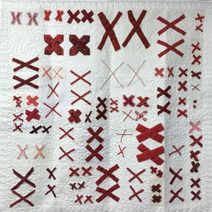 white quilt base embellished with pairs of red X's