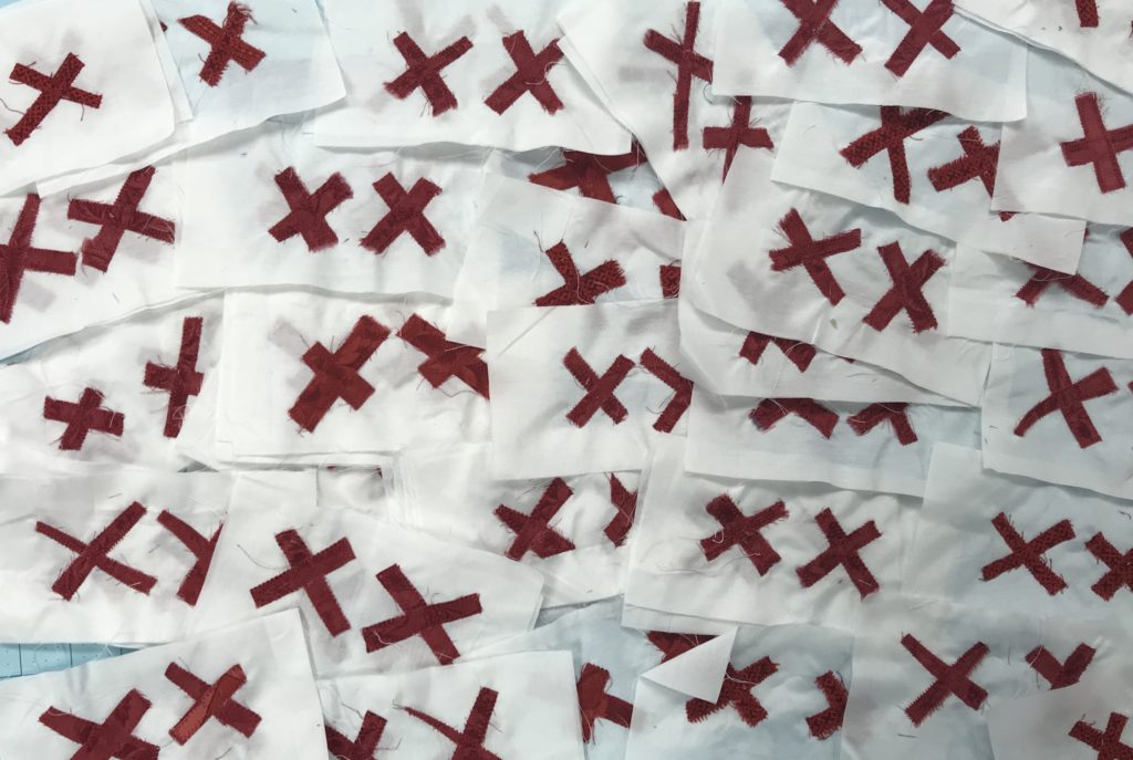 72 white quilt blocks, each embellished with a pair of red X's