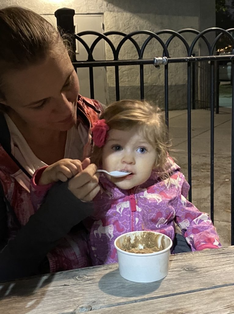 a woman feeds a little girl a spoonful of ice cream
